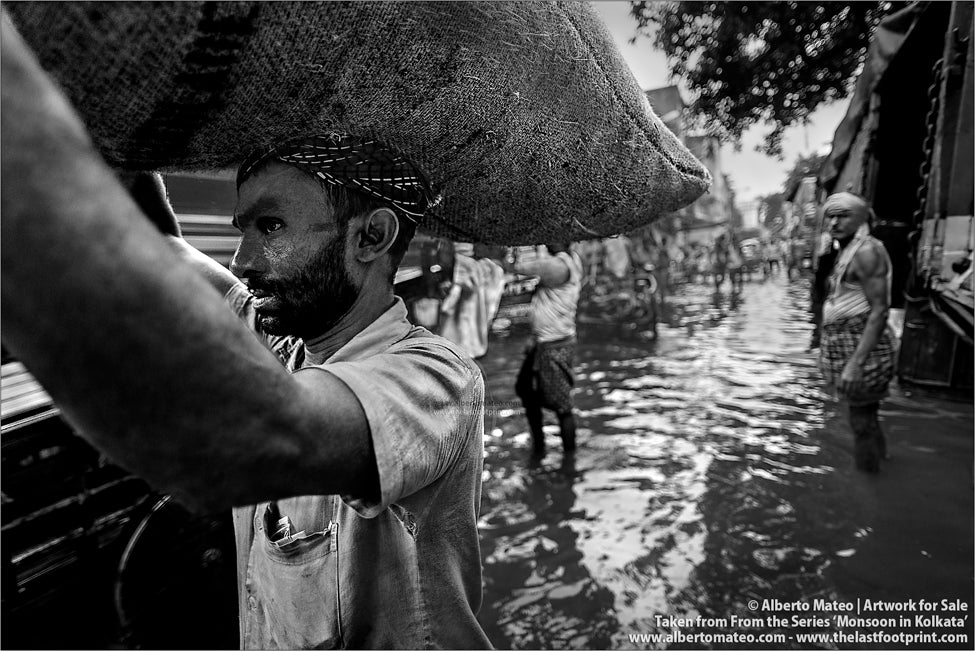 Porter carrying burdens, Bara Bazar docks, Monsoon rain, Shibpur, Kolkata, Bengal, India.
