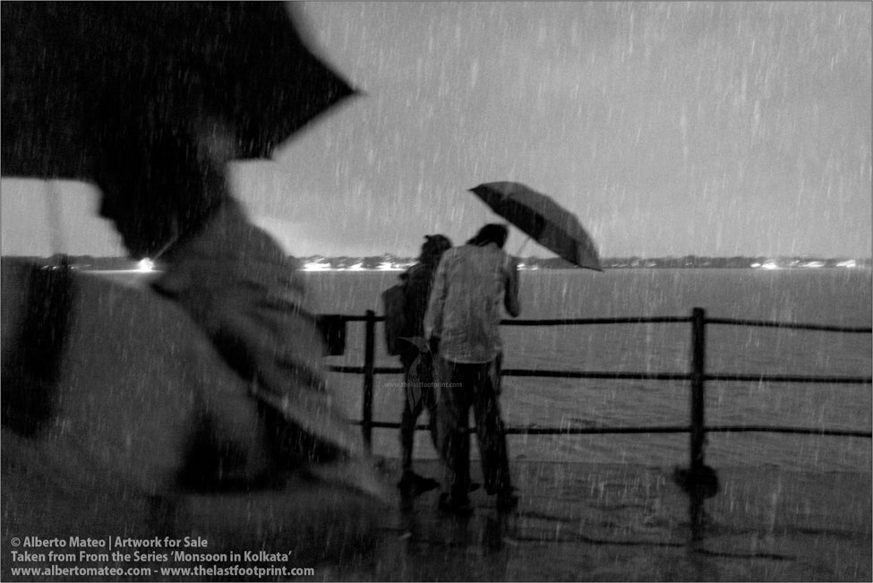 Two men chatting under umbrella next to Hooghly River, Kolkata, Bengal, India.