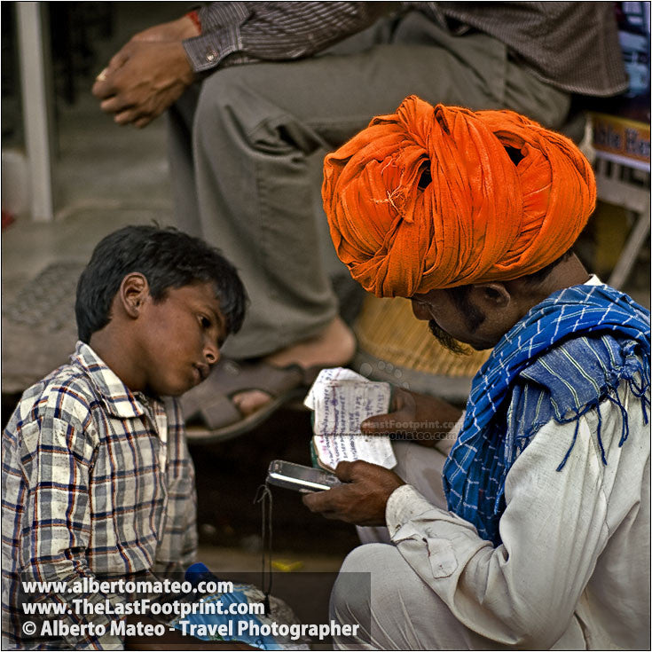Father and son consulting agenda, Pushkar Camel Fair, Rajastan, India. | Cropped detail.